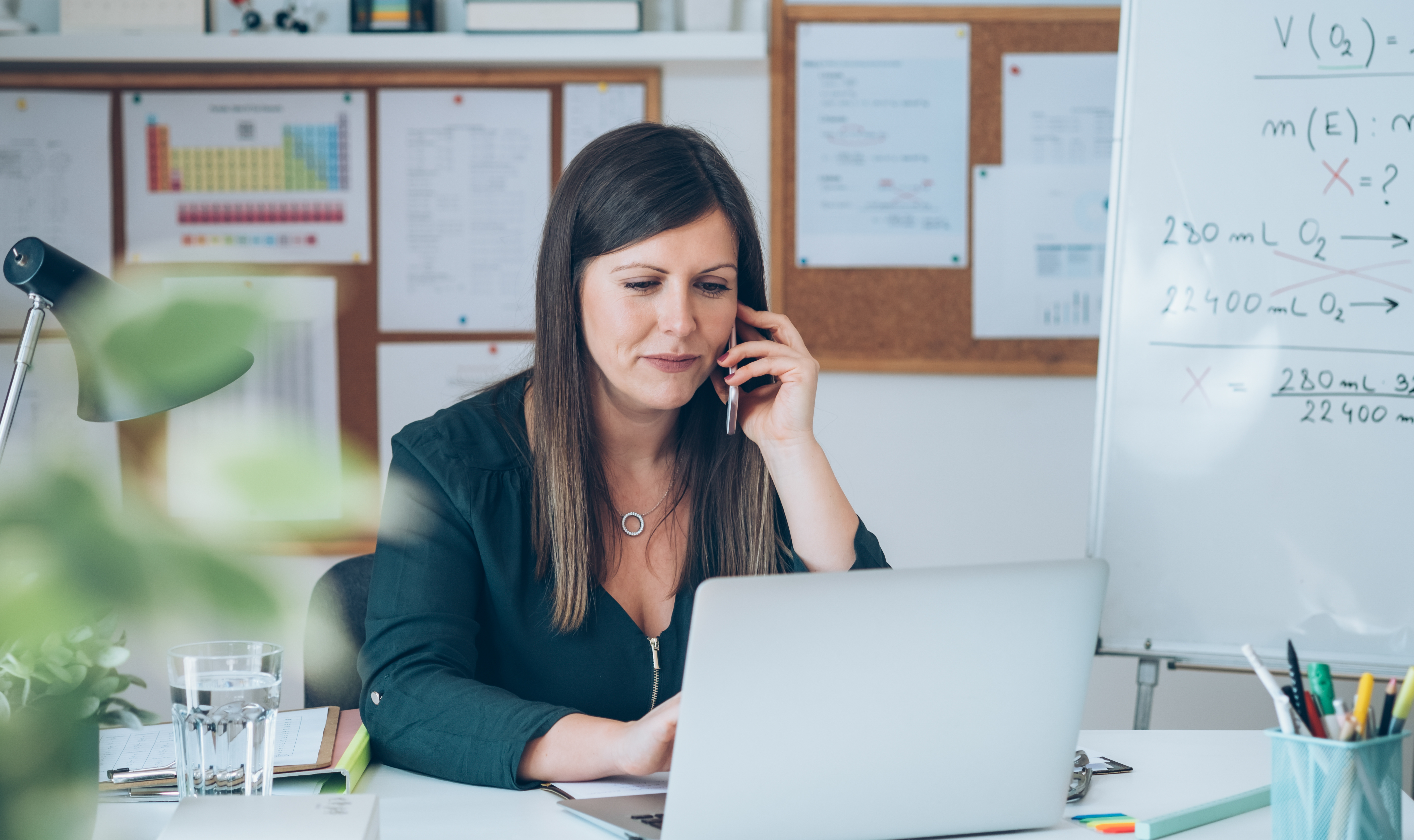 Et billede af en person, der sidder ved skrivebord og snakker i telefon.